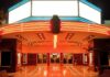 Entrance of a vintage movie theater illuminated by neon lights at night
