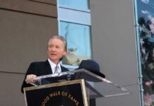 A man in formal attire speaking at a podium during a Hollywood Walk of Fame ceremony