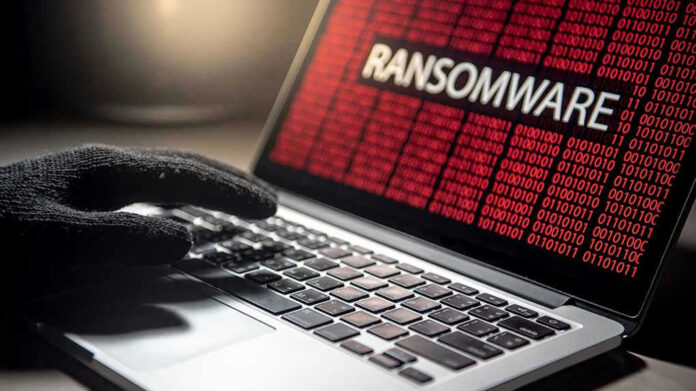 Gloved hand on laptop with ransomware screen