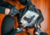Gloved hands around bag with money and gun.