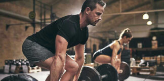 Man and woman lifting barbells in gym.
