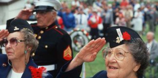 Elderly women in military attire saluting during a veterans ceremony