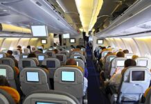 Interior view of an airplane with passengers seated and using inflight entertainment screens