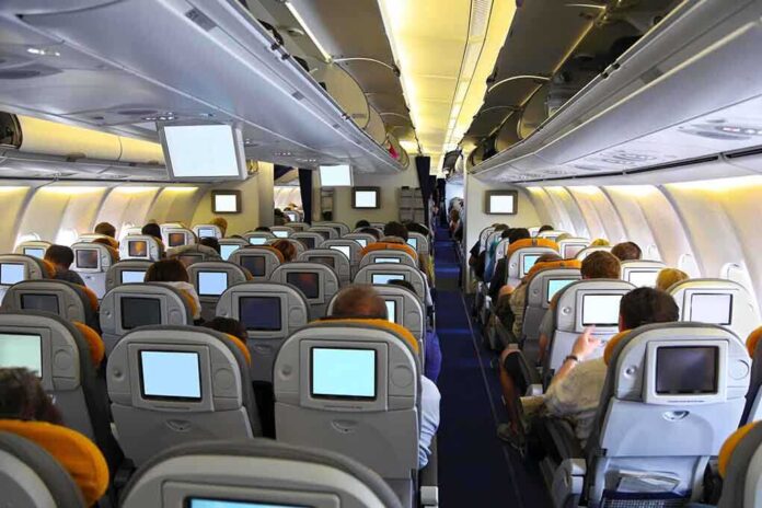 Interior view of an airplane with passengers seated and using inflight entertainment screens