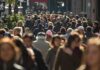 A crowded urban street filled with pedestrians walking in various directions