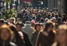 A crowded urban street filled with pedestrians walking in various directions