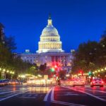 The U.S. Capitol building illuminated at night with city traffic in the foreground