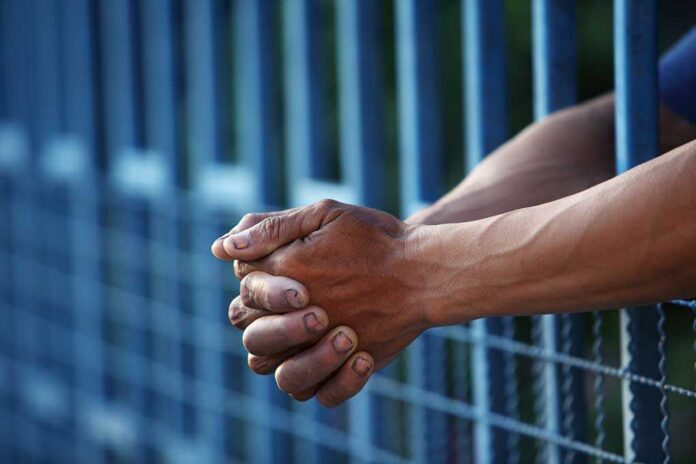 Close up of clasped hands resting on a blue fence