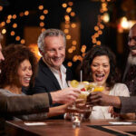 Daily Beer Habit—Shocking New Health Threat People laughing while clinking glasses at a bar