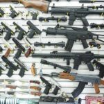 Wall display of various firearms in a store.
