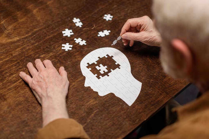 Elderly person completing head-shaped jigsaw puzzle.