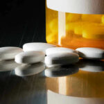 Big Pharma’s Statin Push: Who Really Benefits? White pills beside an orange pill bottle.