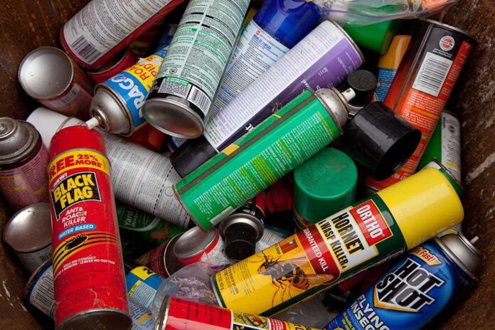 A pile of discarded spray cans in a garbage bin