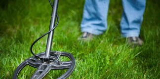 A metal detector being used on grassy ground