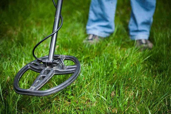 A metal detector being used on grassy ground