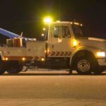 Tow truck with flashing lights parked at night