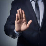 Man in suit with hand raised, signaling stop.