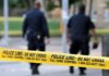 Police officers walking past caution tape at a crime scene
