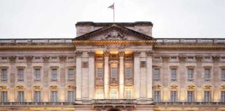 Front view of Buckingham Palace with illuminated facade and British flag