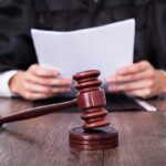 A judge holding documents with a gavel in the foreground