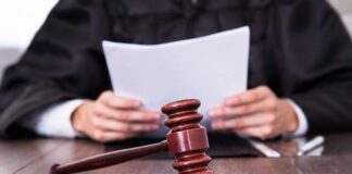A judge holding documents with a gavel in the foreground