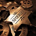 A collection of vintage sheriff badges arranged on a dark surface