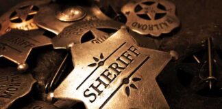 A collection of vintage sheriff badges arranged on a dark surface
