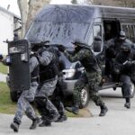 Policemen Wounded — SWAT Team Mobilized SWAT team members in tactical gear responding to a situation