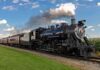 A vintage steam locomotive pulling passenger cars on a railway track