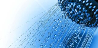 Close-up of a shower head with water droplets against a blue background