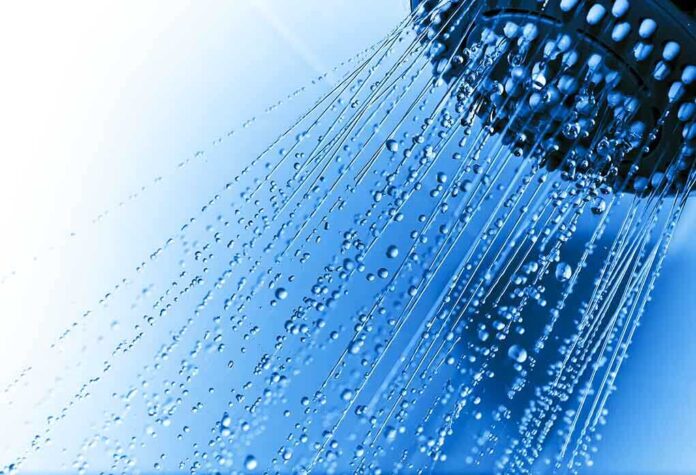 Close-up of a shower head with water droplets against a blue background
