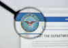 Magnifying glass over Department of Defense logo.