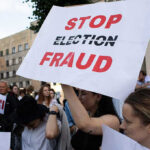 People holding Stop Election Fraud protest signs.