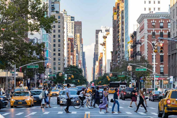Busy city street with pedestrians, cars, and tall buildings.