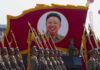 Military parade featuring soldiers and a large banner of Kim Il-sung