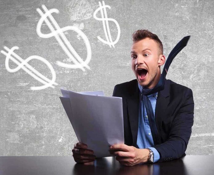 Excited businessman holding documents with dollar signs in the background