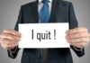A man in a suit holding a sign that says I quit!