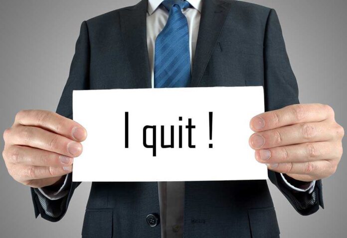 A man in a suit holding a sign that says I quit!