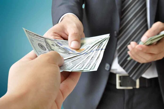 Two hands exchanging cash in a business setting