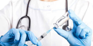 Doctor filling syringe with vaccine from vial.