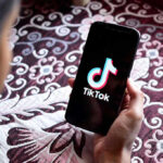 AI Bombshell ROCKS TikTok — Millions Fooled Hand holding phone showing TikTok logo.