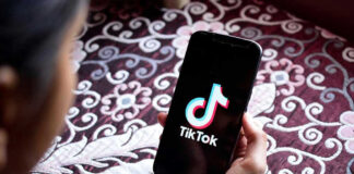 Hand holding phone showing TikTok logo.