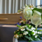 Musician Icon GONE–End of an ERA White roses in front of a casket.