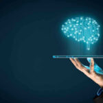 Hand holding tablet projecting digital brain hologram.