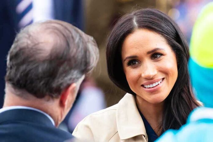 A woman smiling while engaging in conversation at an outdoor event