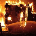 A firefighter battling a large house fire at night