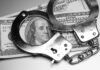Handcuffs placed over a stack of hundred dollar bills