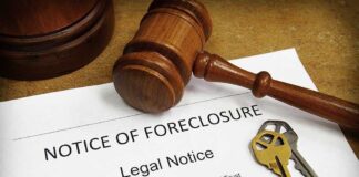 A gavel resting on a legal notice of foreclosure with keys beside it
