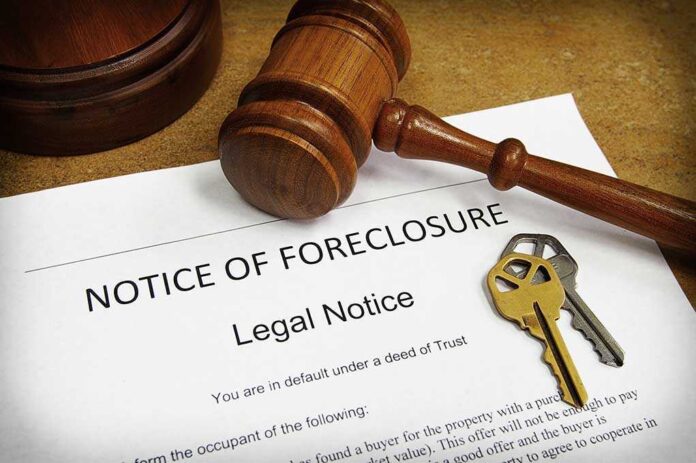 A gavel resting on a legal notice of foreclosure with keys beside it
