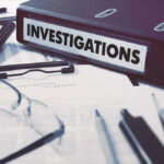 Documents and binder labeled Investigations on desk.